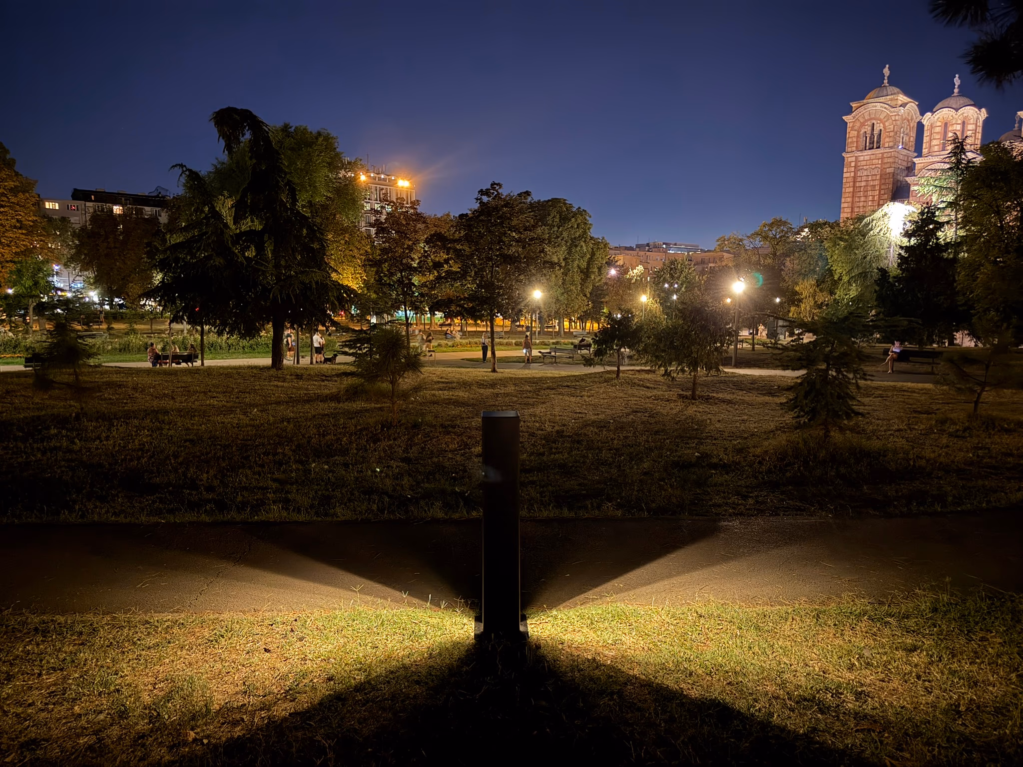 LED Bollard at night in a park, city skyline and church lit up behind it